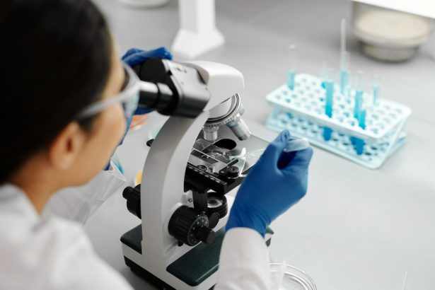 Cientista realiza pesquisa em laboratório usando microscópio e conta-gotas.