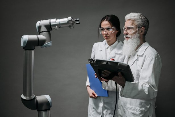 Pesquisadores examinam um braço robótico em um laboratório de tecnologia.