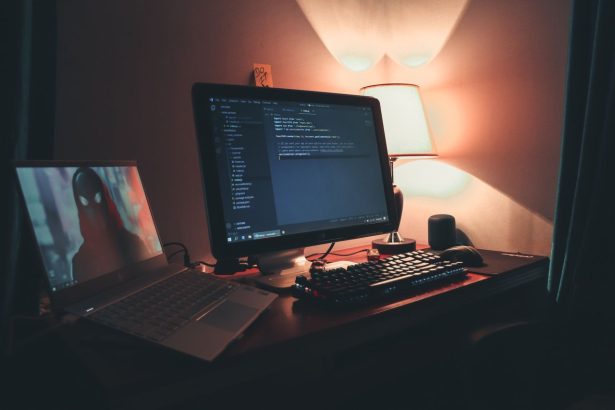 Escritório doméstico iluminado com dois monitores exibindo um ambiente de programação e desenvolvimento.