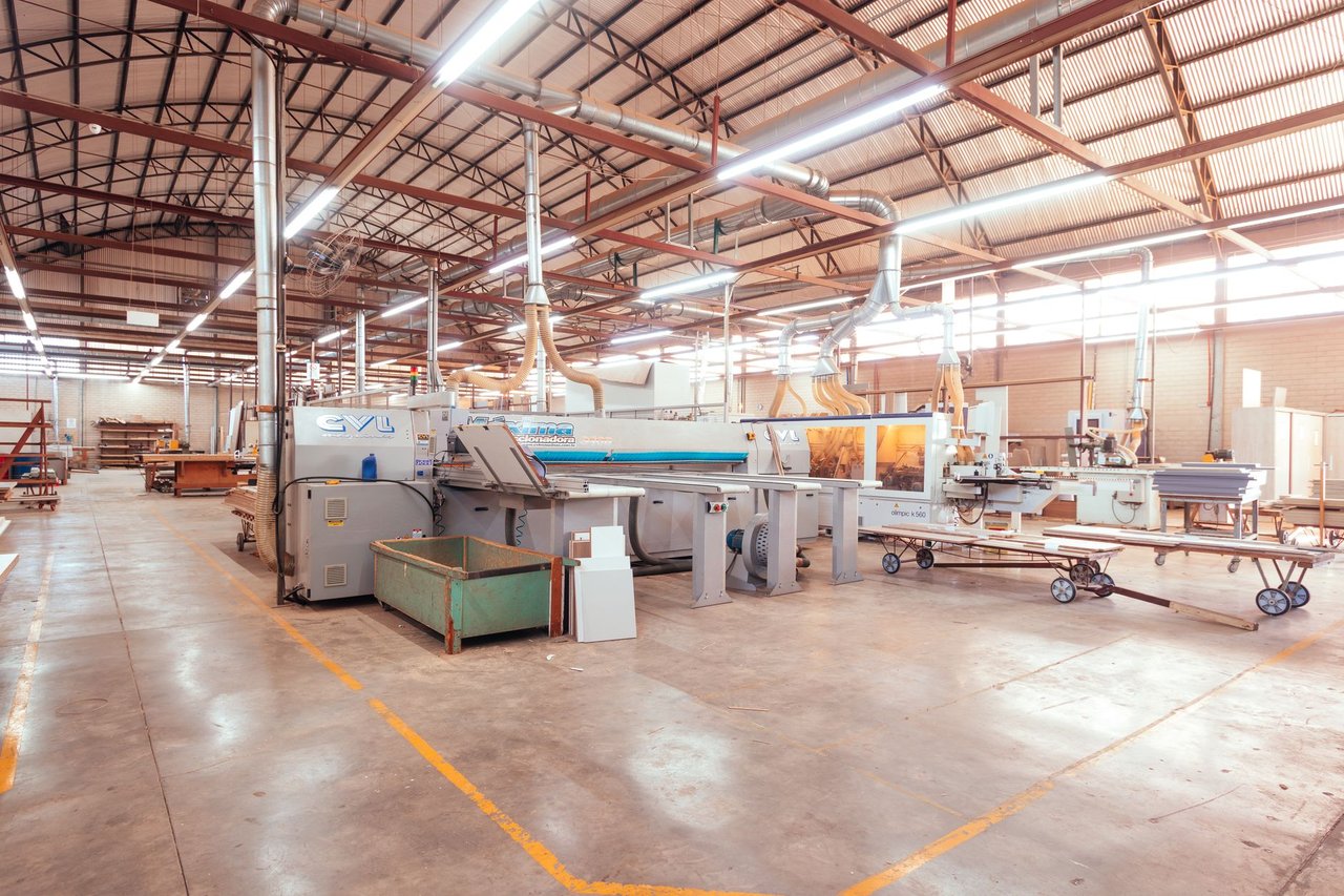 Vista ampla de uma fábrica moderna e organizada, com máquinas industriais em operação.